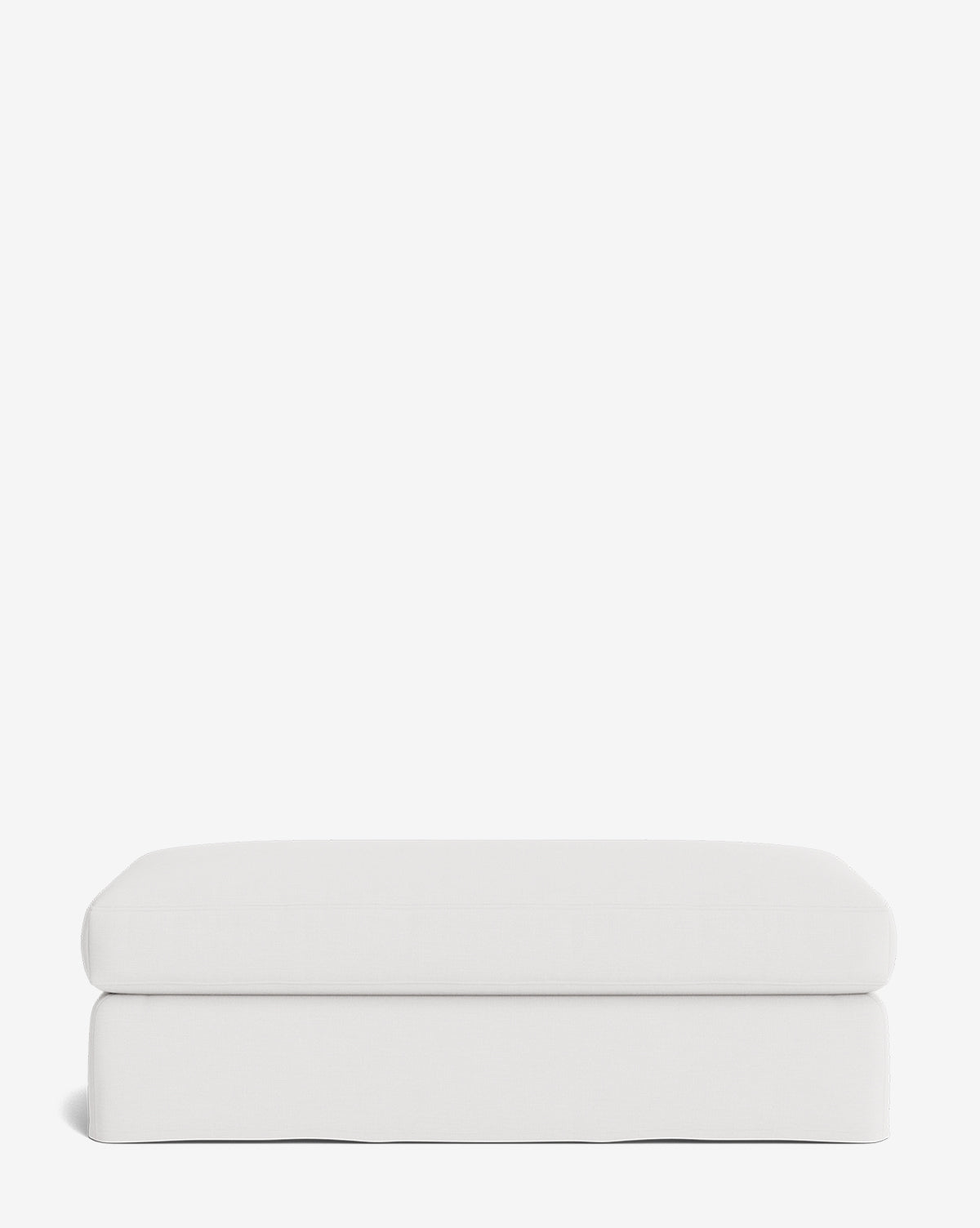 The Macy Slipcover Ottoman is a minimalist, rectangular white ottoman with a soft cushioned top and smooth edges—an ideal, versatile addition to your living room decor, shown against a plain white background by Vendixs