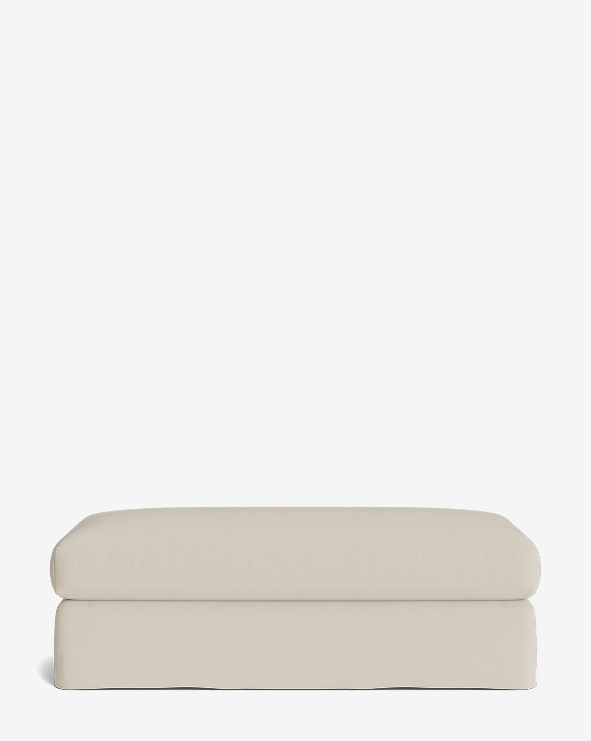 The Macy Slipcover Ottoman is a rectangular, light beige ottoman with clean lines and a soft cushioned top, perfect for customizable living room furniture, shown against a plain white background by McGee & Co.