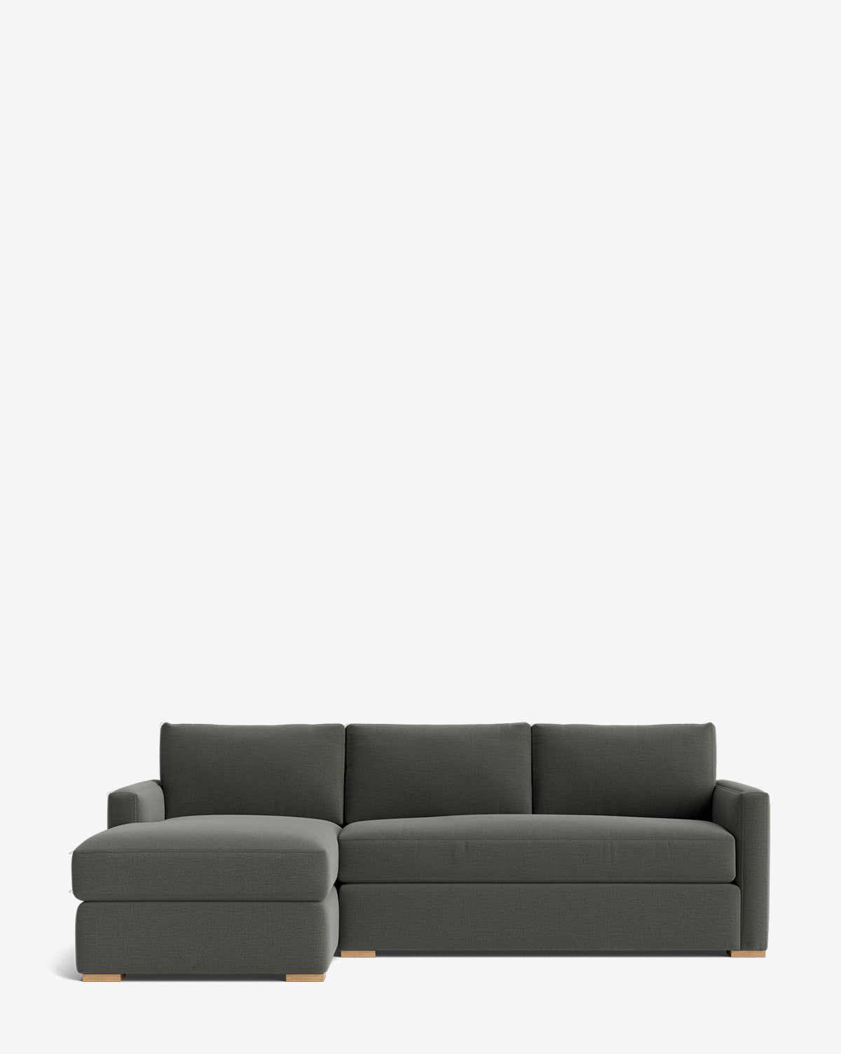 The Community Macy Upholstered Chaise Sectional 101 in dark gray features three seat and back cushions, a left-facing chaise lounge, clean lines, light wooden block legs, and a simple silhouette on a white background. Vendixs