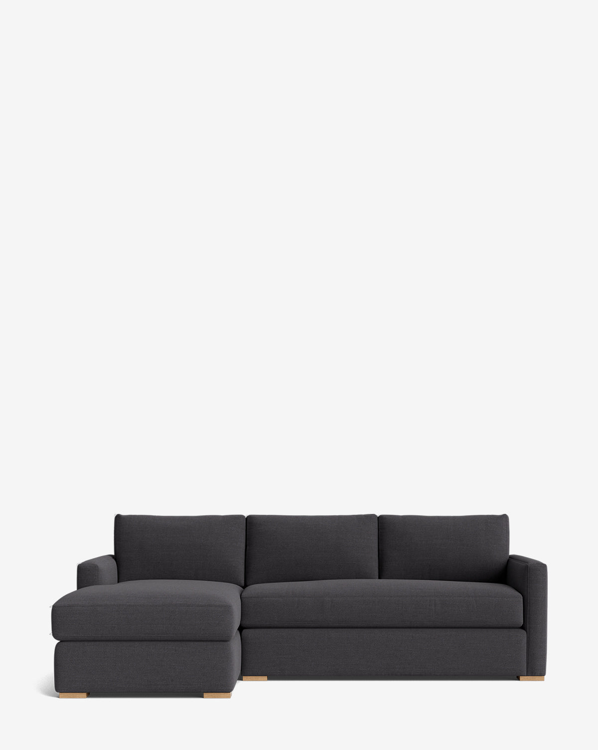 The Community Macy Upholstered Chaise Sectional 101 features a modern dark gray design with a left-facing lounge, three back cushions, and low wooden block feet, shown against a plain white background, Vendixs