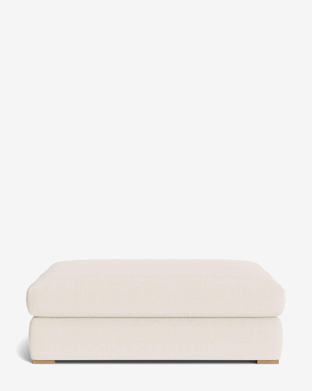 The Macy Upholstered Ottoman features a modern cream-colored design with rounded edges and low wooden feet, making it perfect for living room furniture, by Vendixs Shown against a plain white background.