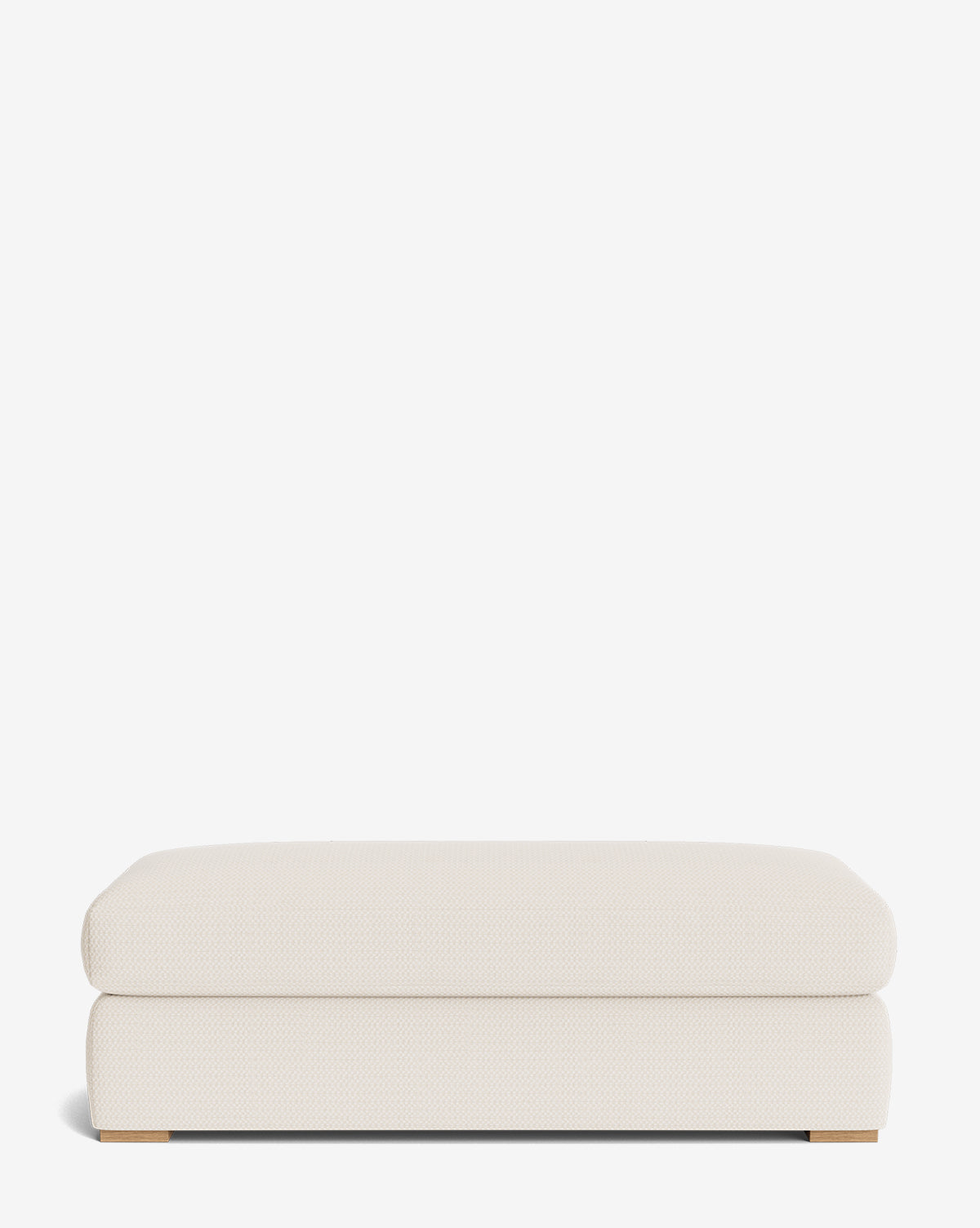 The Macy Upholstered Ottoman is a rectangular, low-profile piece in off-white fabric with smooth rounded edges, a minimalist design, and small wooden feet visible at the bottom corners—perfect for modern living rooms, by Vendixs