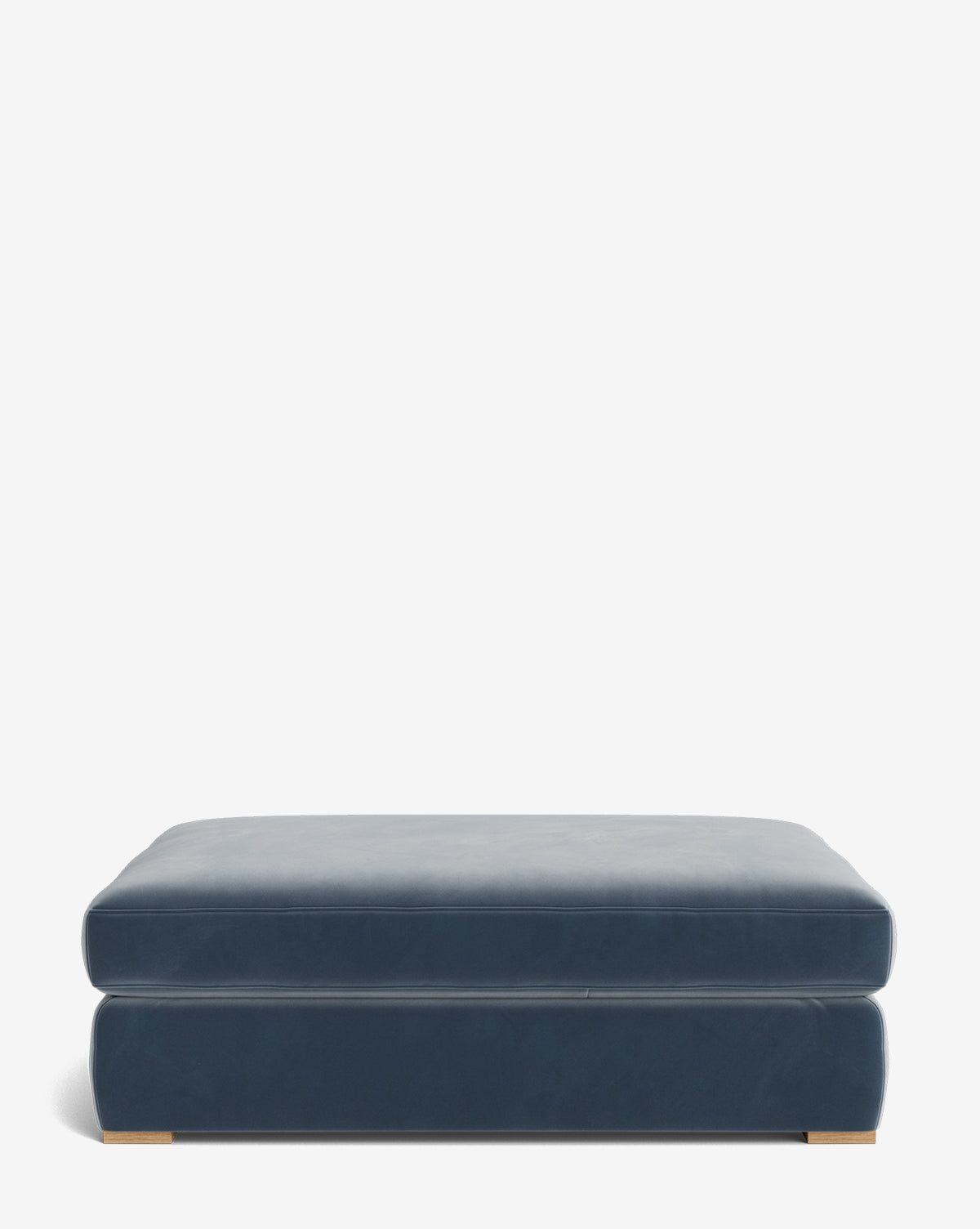 The Macy Upholstered Ottoman is a large, rectangular blue ottoman with a smooth upholstered surface and wooden feet, ideal for living room furniture, shown against a plain white background, by Vendixs