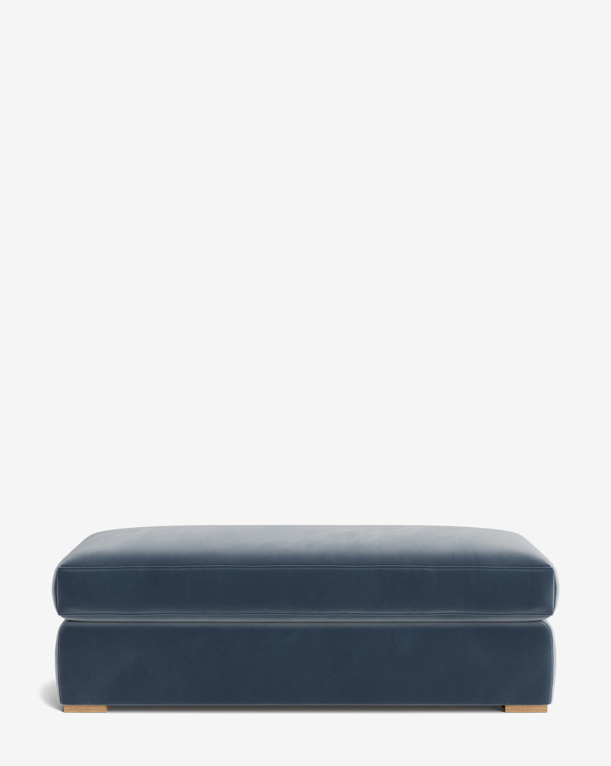 The Macy Upholstered Ottoman is a large, rectangular blue piece with smooth upholstery and low wooden feet—ideal for versatile living room use—shown against a plain white background by Vendixs