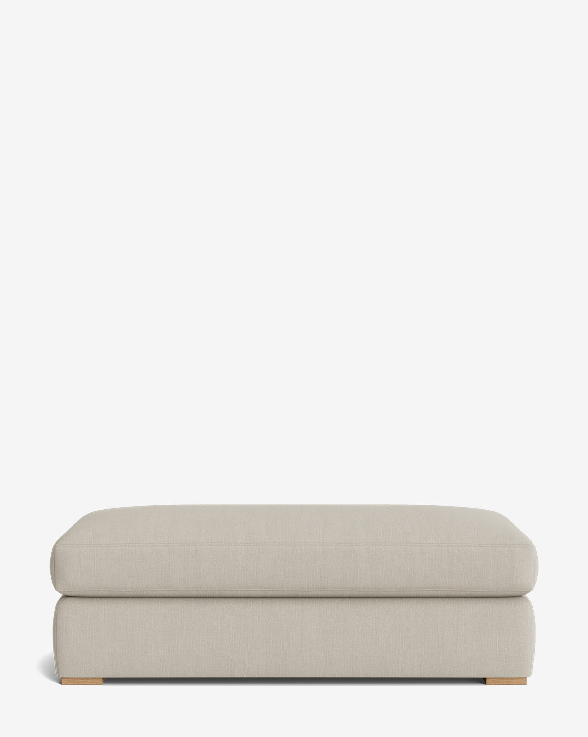 The Macy Upholstered Ottoman is a modern rectangular piece with a soft cushioned top and subtle wooden feet, offering versatile living room seating, by McGee & Co. It is shown against a plain white background.