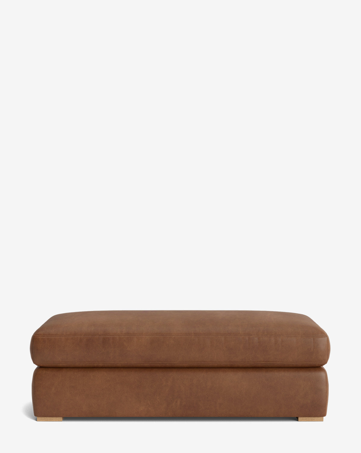 The Macy Upholstered Ottoman features a rectangular shape, brown leather upholstery, and small square metallic feet. Its simple modern design makes it perfect for the living room, shown here against a plain white background by Vendixs