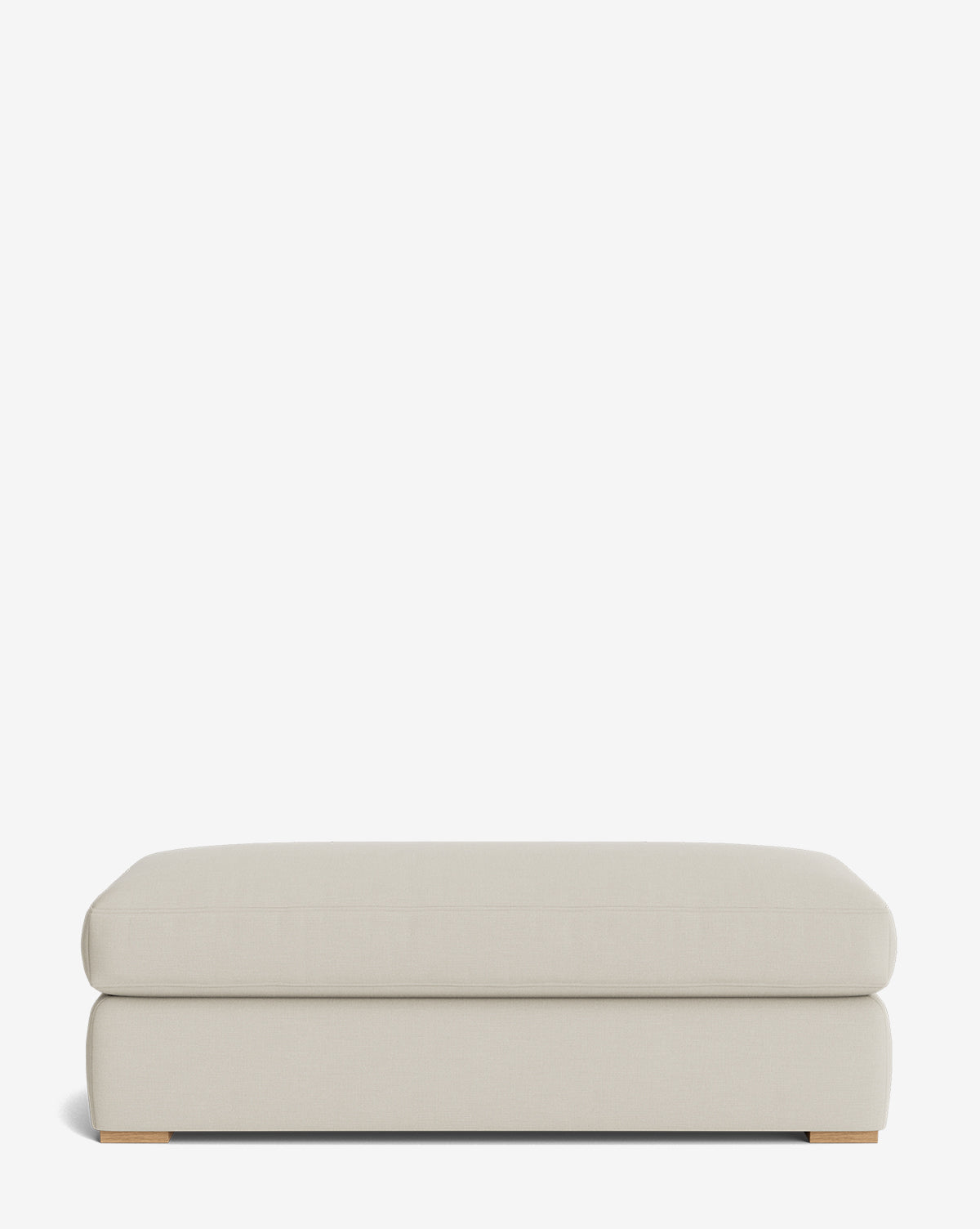 The Macy Upholstered Ottoman features a rectangular shape, light beige upholstery, clean lines, and low wooden feet. This versatile living room piece is shown against a plain white background, by Vendixs