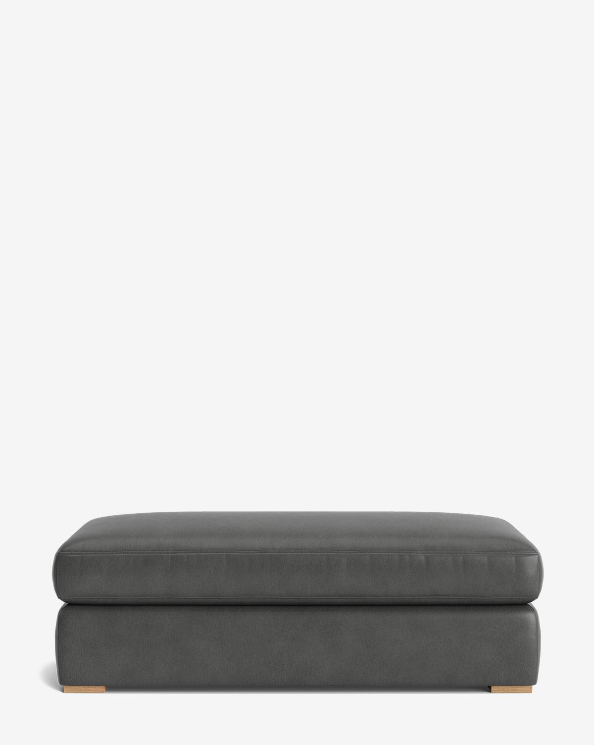 The Macy Upholstered Ottoman is a modern, rectangular piece in dark gray with a smooth surface and low wooden feet, ideal for living room furniture and shown against a plain white background, by Vendixs