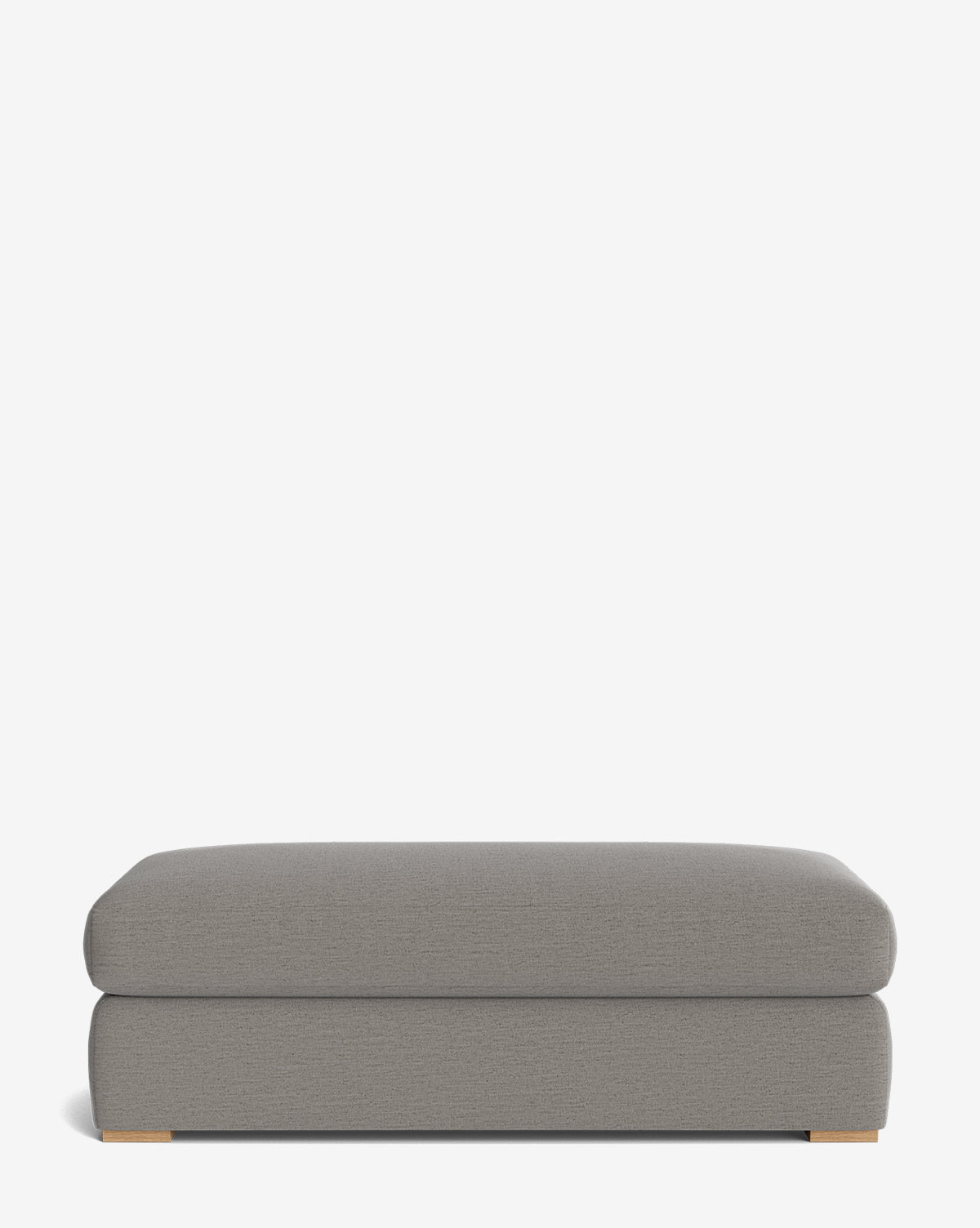 The Macy Upholstered Ottoman is a rectangular, gray ottoman with low wooden feet shown against a white background—perfect for the living room, effortlessly combining comfort and style, by McGee & Co.