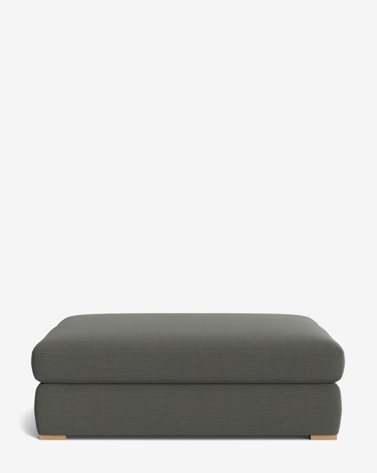 The Macy Upholstered Ottoman is a rectangular, dark gray piece with rounded edges and low wooden feet, shown against a plain white background by McGee & Co.