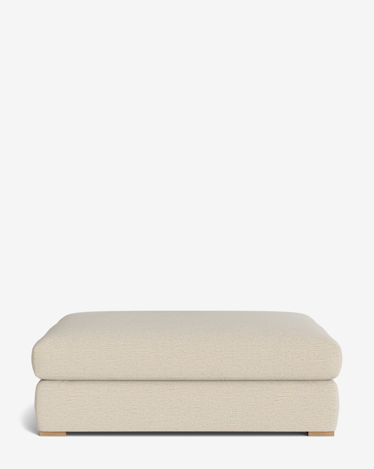 The Macy Upholstered Ottoman is a beige, rectangular piece with a soft cushioned top, minimal seams, and low wooden feet—an elegant addition to any living room, shown against a plain white background by McGee & Co.