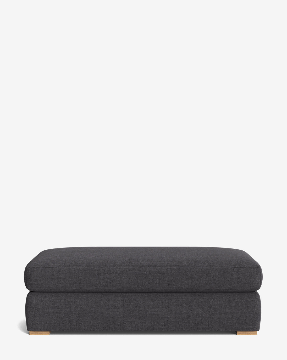 The Macy Upholstered Ottoman is a rectangular, dark gray piece with a low profile, flat top, and small wooden feet—ideal customizable ottoman living room furniture—shown against a plain white background by McGee & Co.
