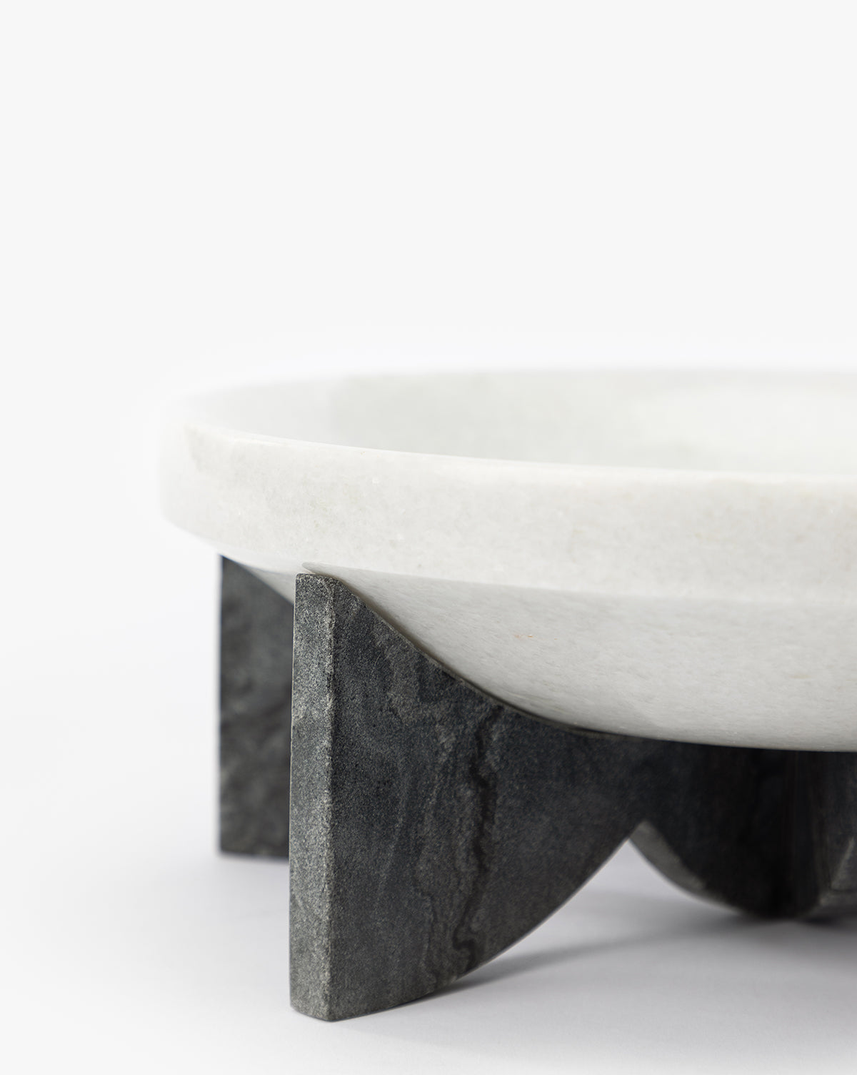 The Mahoney Bowl, featuring a sculptural white marble form, is displayed on a dark three-legged stone stand against a plain white background, by Vendixs
