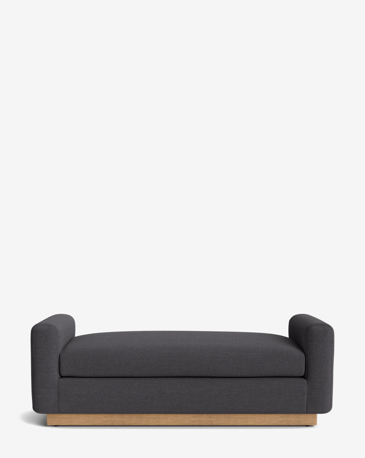 The Mansfield Bench is a handcrafted modern bench with dark gray upholstery, low thick armrests, and a light wooden base—offering comfort and contemporary style, by McGee & Co. Set against a plain white background.