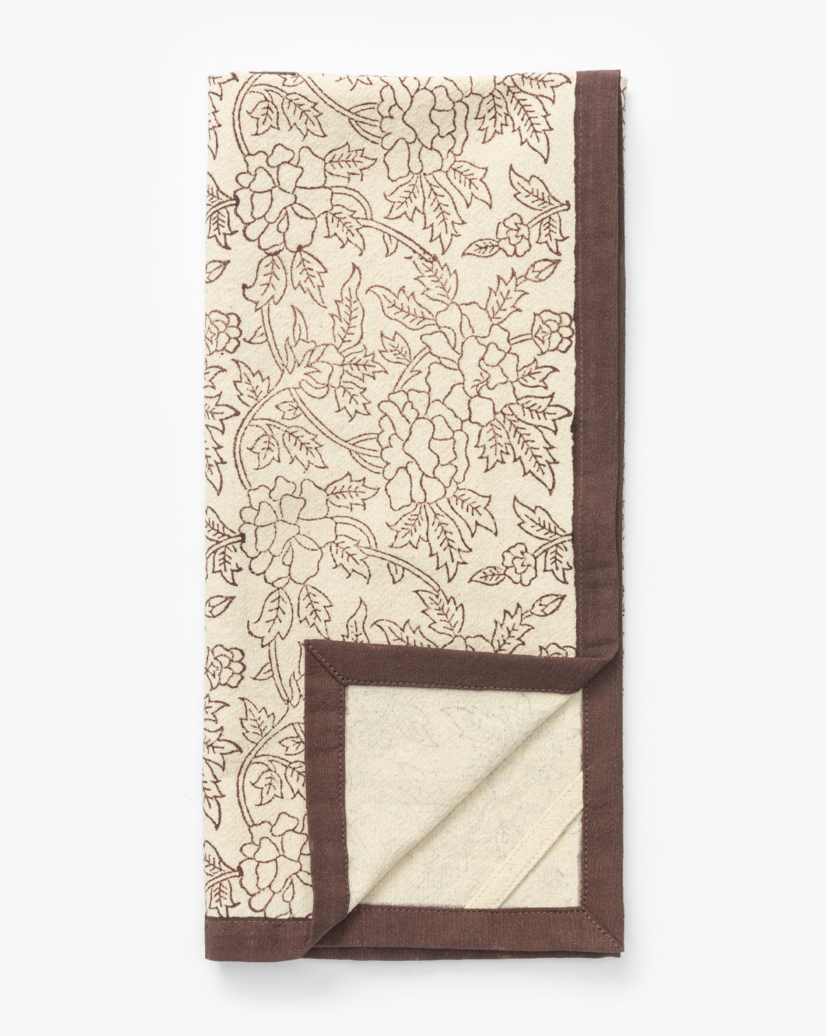 The Marceline Cotton Tea Towel, in cream with a brown floral pattern and border, is block printed for charm and shown folded with a corner turned up—an elegant accent for your kitchen decor, by Vendixs