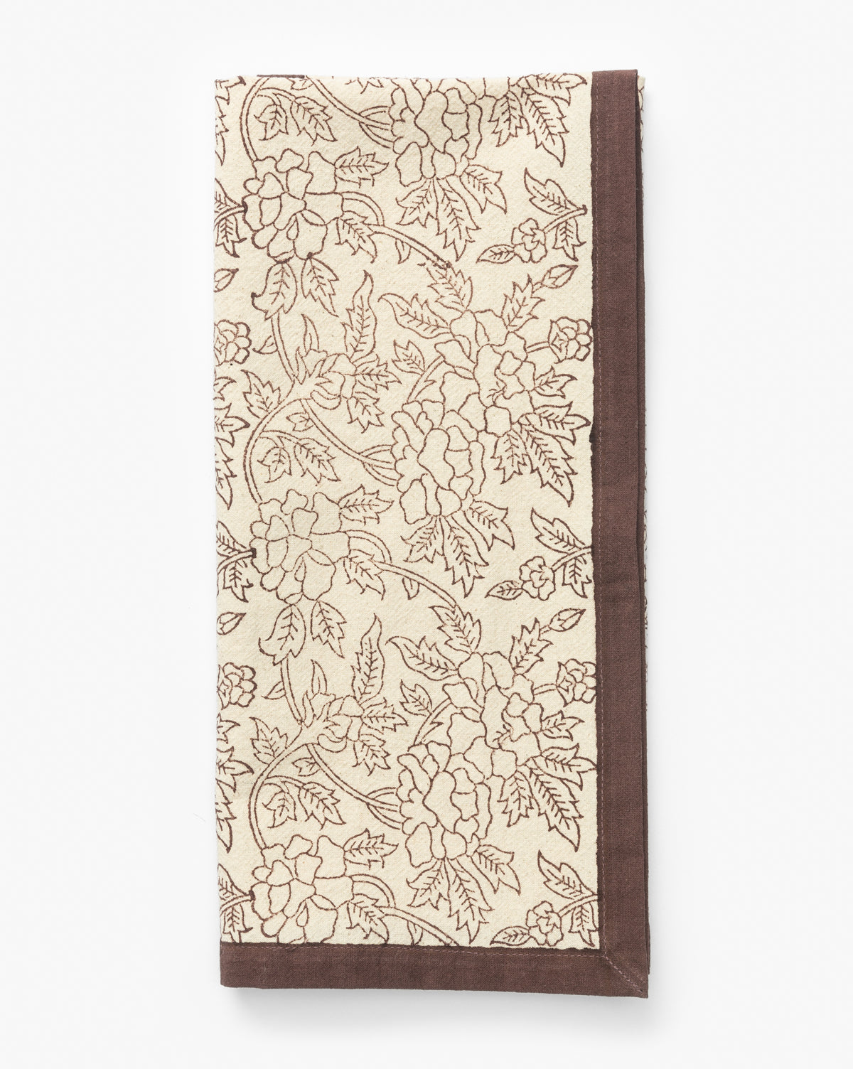 A beige cloth napkin with a brown floral and leaf pattern and a solid brown border is neatly folded on a white background—ideal for kitchen decor or pairing with the Marceline Cotton Tea Towel, by Vendixs
