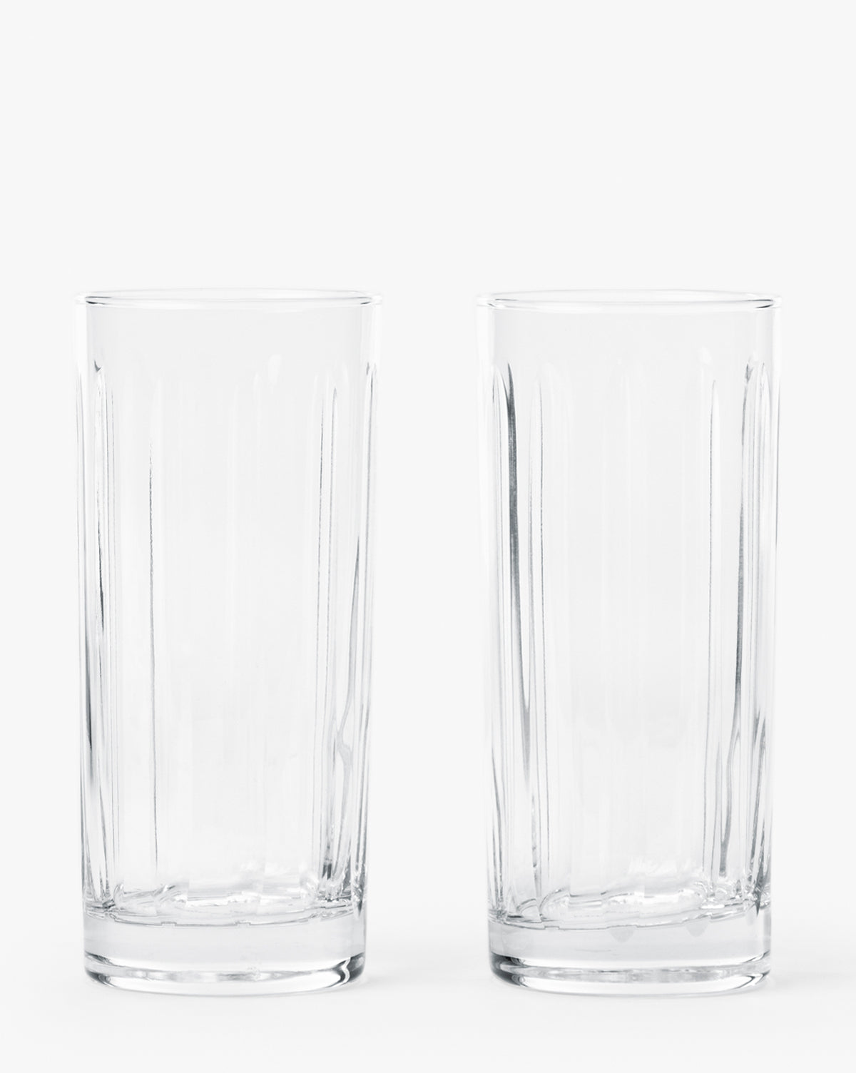 A set of two empty, clear Marick Highball Glasses with classic silhouettes stands side by side on a plain white background by McGee & Co.