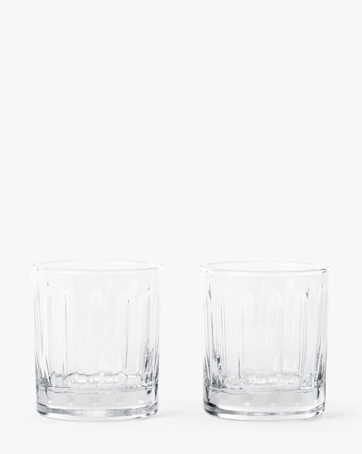Two empty, clear Marick Tumblers (Set of 2) featuring subtle vertical patterns and classic silhouettes are placed side by side on a plain white background, by McGee & Co.