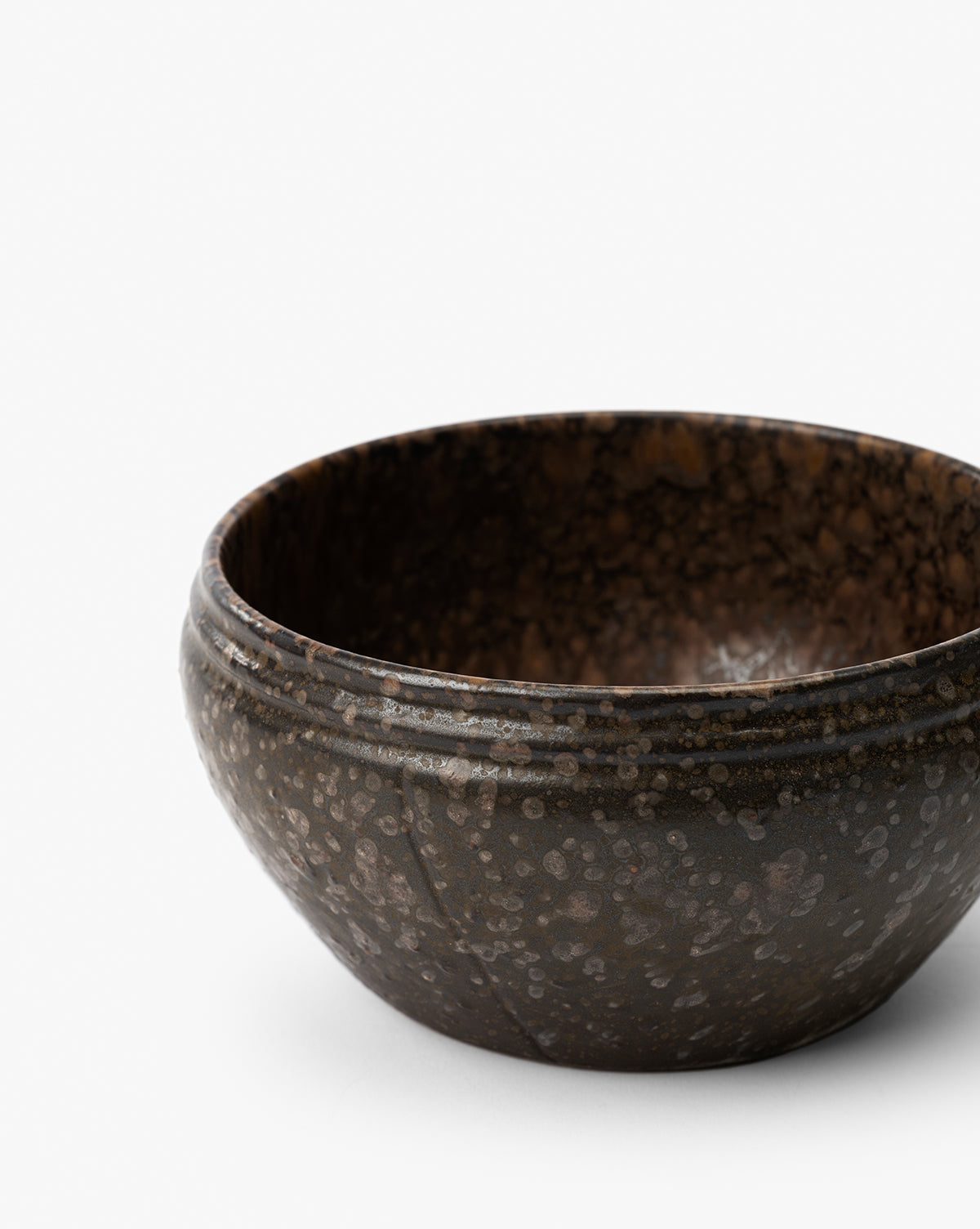 The Mariella Stoneware Bowls (Set of 4) feature a round shape, dark speckled finish, and gently curved rims. Their handmade quality and rustic design offer a simple elegance, perfect for modern or casual table settings by Vendixs