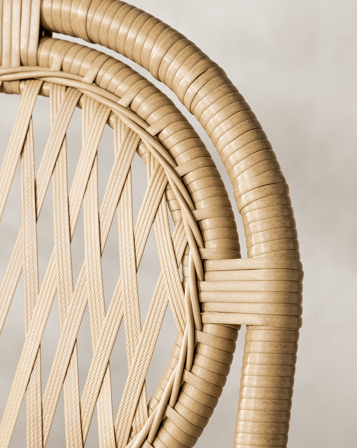 Close-up of the Marisol Indoor/Outdoor Counter Stool by Makerspalm, showing its handwoven wicker backrest with interlaced diagonal strips and a smooth circular frame in light tan, set against a neutral, blurred background. Set of 2. Vendixs