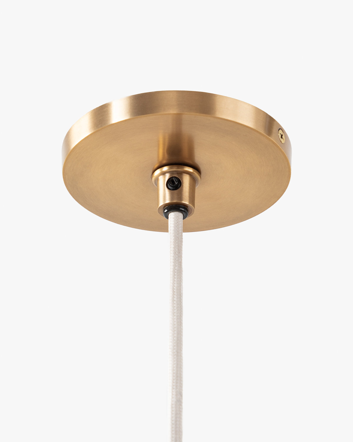 A close-up of a round brass ceiling canopy with a white cord, set against a white background—part of the Vendixs x Loeffler Randall Maude Glass Pendant collection, by Vendixs