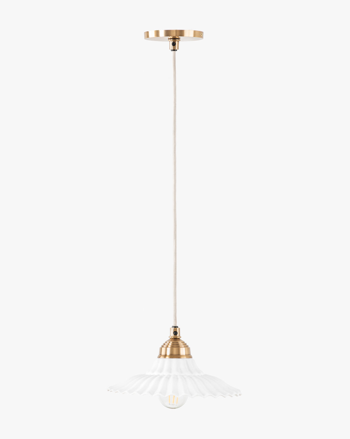 The Vendixs x Loeffler Randall Maude Glass Pendant features elegant brass hardware, a beige cord, and a white fluted glass shade suspended gracefully from the ceiling by McGee & Co.
