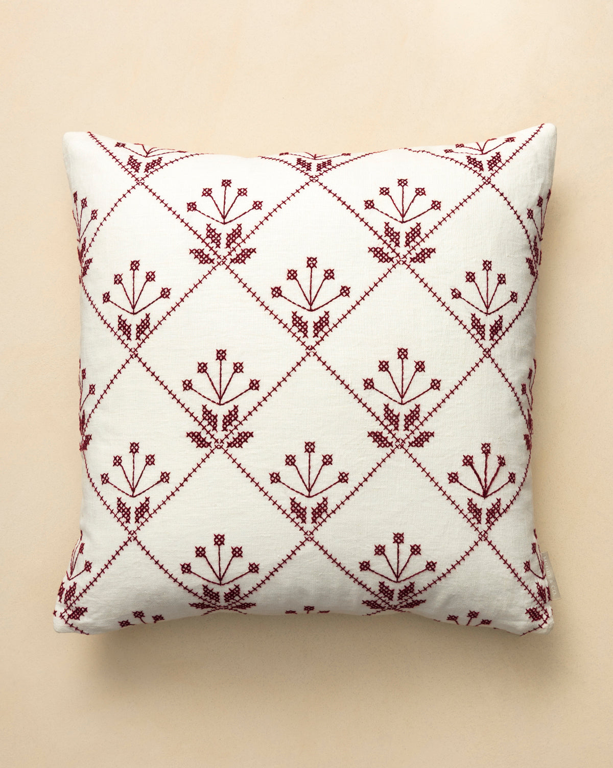 The McCallister Pillow Cover features a square cream base adorned with maroon stitched flowers in diamond grids—ideal for vintage decor lovers or adding charm to your holiday home, by Vendixs