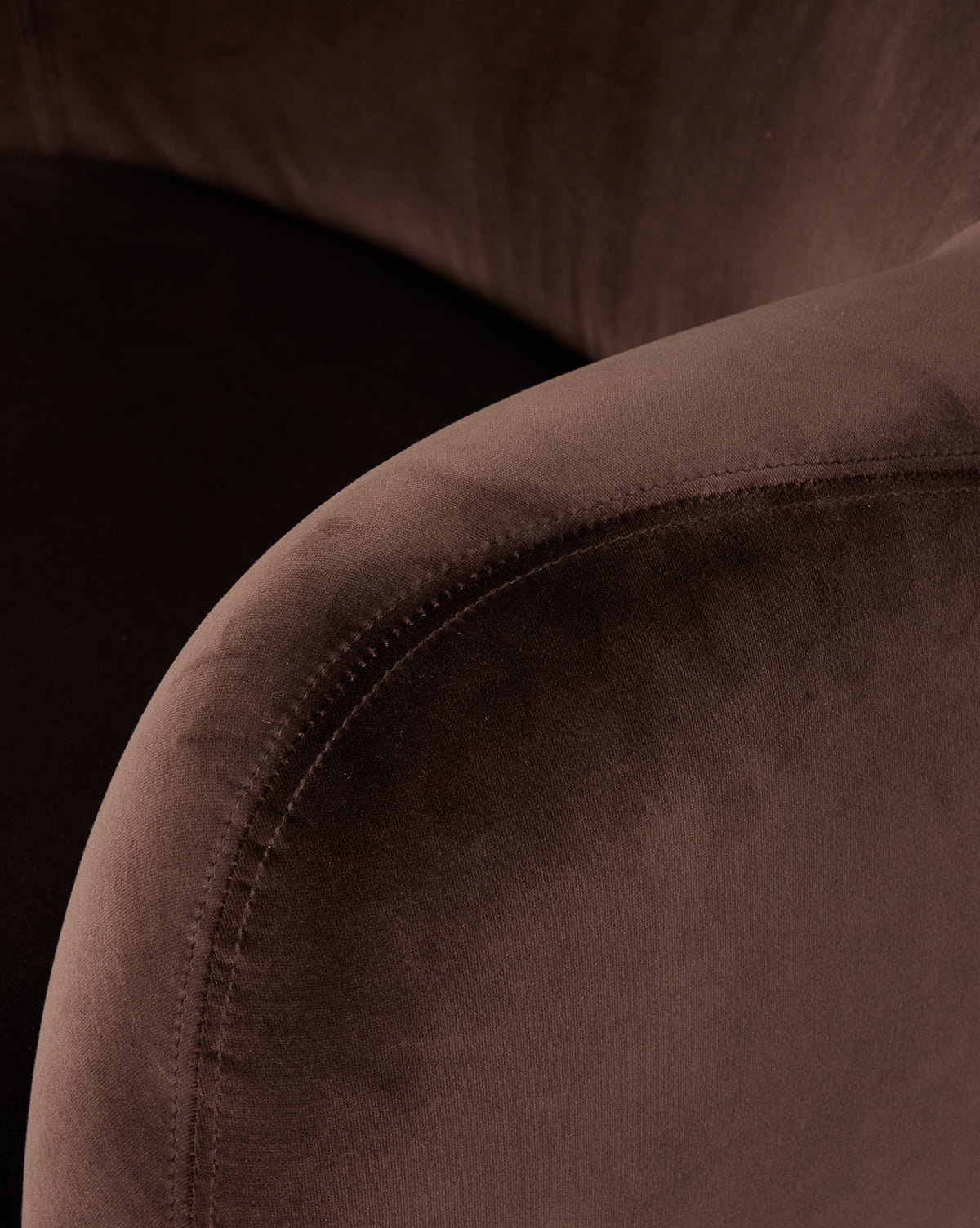 Close-up of the Moira Swivel Chair in cocoa fabric, featuring its curved armrest and seat with a soft, plush texture under subtle lighting, by McGee & Co.