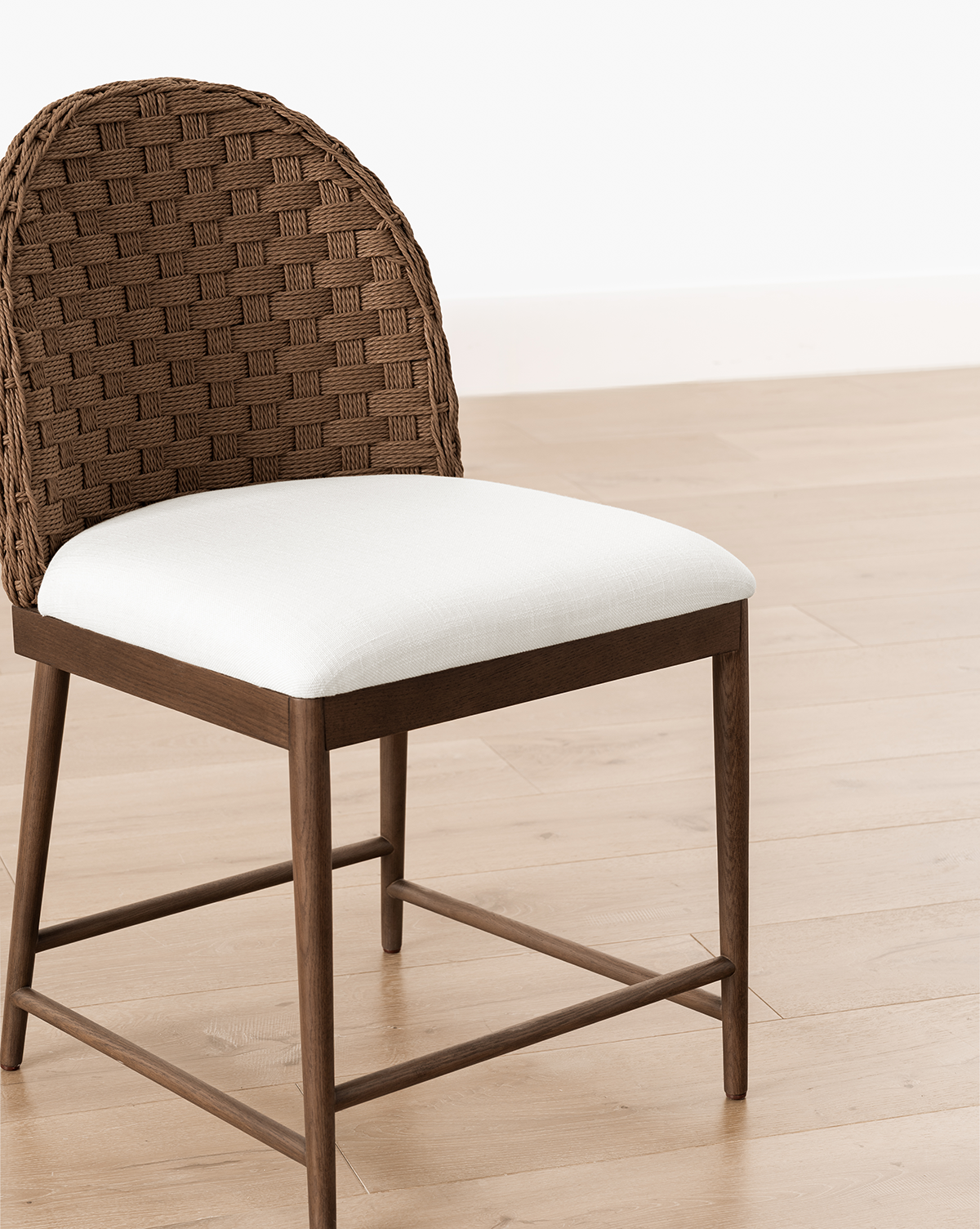 The Molly Dining Chair showcases a woven curved backrest and white cushioned seat, with a modern design crafted from solid oak—ideal for light wood floors and white walls, by Vendixs
