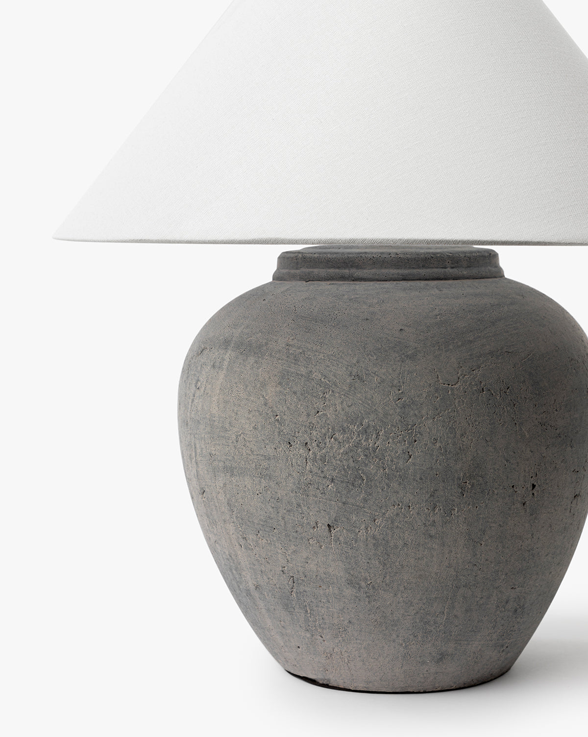 A close-up of the Montague Table Lamp with a textured gray ceramic base and a white cone-shaped lampshade, shown against a plain white background, by Vendixs