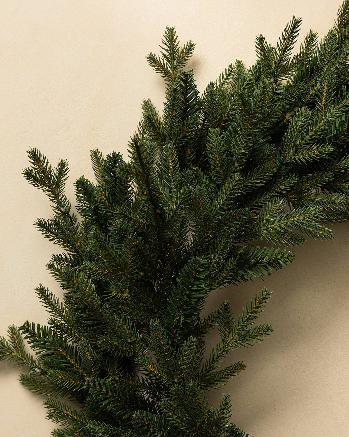 The 20" Norway Pre-Lit Indoor/Outdoor Faux Wreath, featuring lifelike greenery, brings festive holiday decor to your space and looks beautiful against a light beige background, by Vendixs