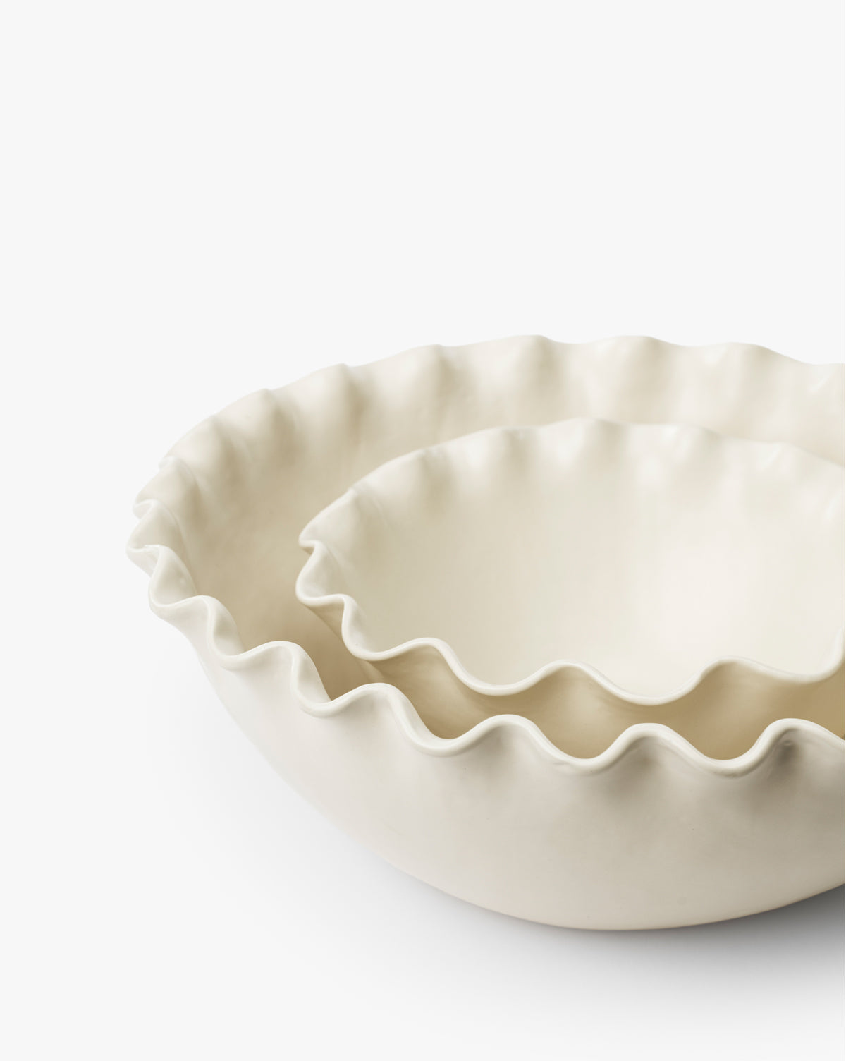 The Olindo Serving Bowls (Set of 2) feature cream-colored bowls with ruffled, wavy edges, perfectly nested together. The smaller vintage-inspired bowl fits neatly inside the larger one against a white background, by Vendixs