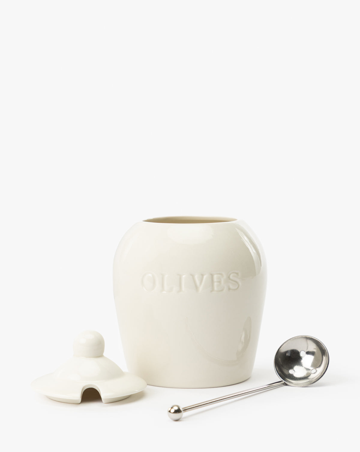 The Olive Stoneware Jar, labeled OLIVES, comes with a matching lid and airtight seal. A silver slotted spoon rests beside it, all displayed against a plain white background, by Vendixs