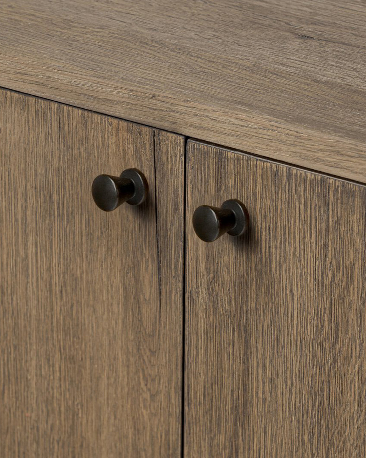 Close-up of two wooden cabinet doors on the Oswin Sideboard, featuring a weathered oak finish with light brown wood grain and round, dark metal knob handles, by Vendixs