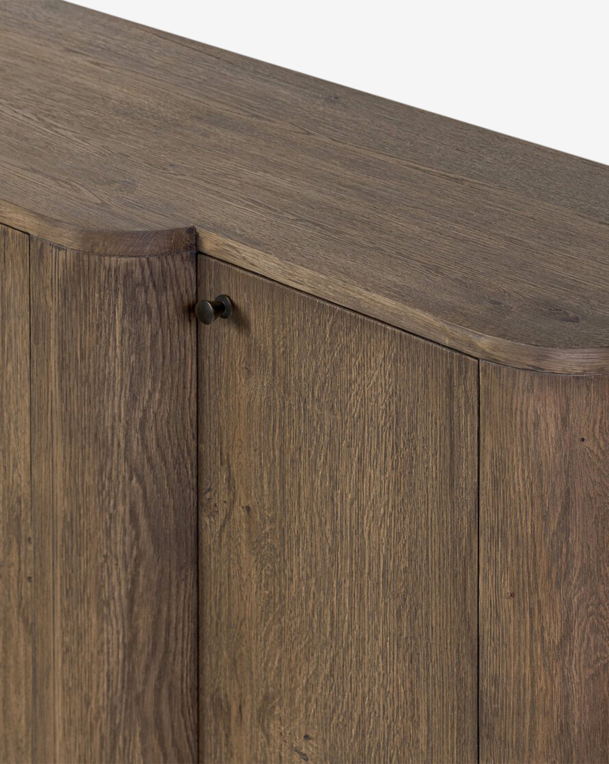A close-up of the Oswin Sideboard highlights its weathered oak finish, showcased wood grain, beveled top edges, and a door featuring a small round handle, by McGee & Co.