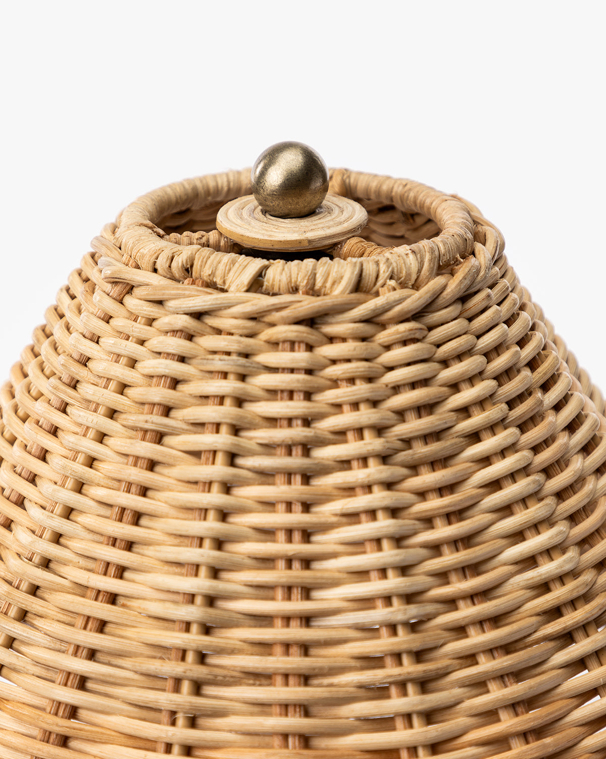 Close-up of the top of the Palmetto Table Lamp, showing its round brass knob on the woven wicker lid, by Vendixs