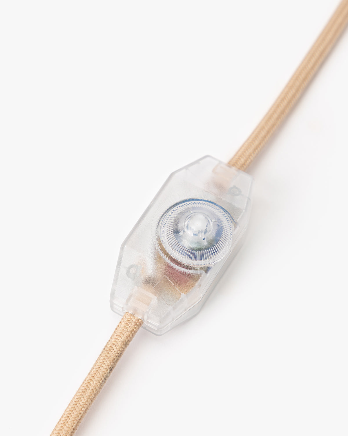A close-up of a transparent inline rotary switch on the beige fabric cord of the Palmetto Table Lamp, ideal for dimming, shown against a white background, by Vendixs