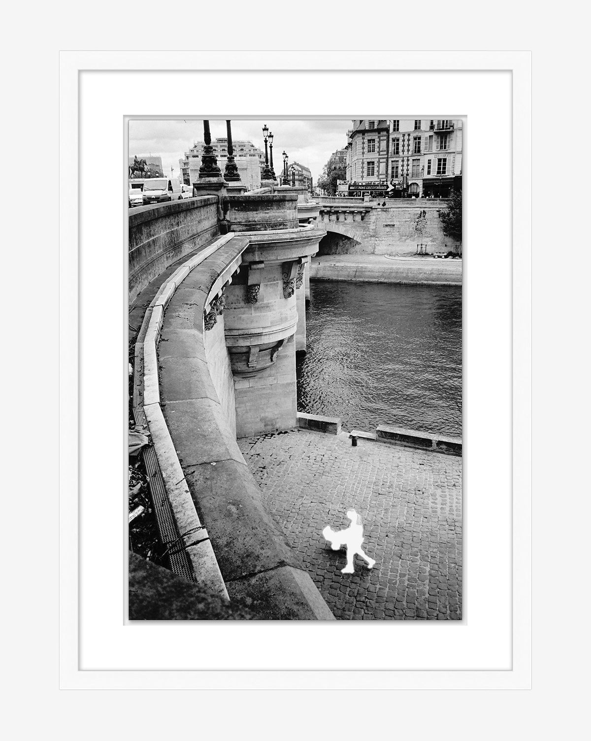 Parisian Promenade is a black and white gallery-quality giclee print of a riverside walkway in Europe, featuring an empty stone path along the water and a silhouetted white cartoon-style figure by McGee & Co.