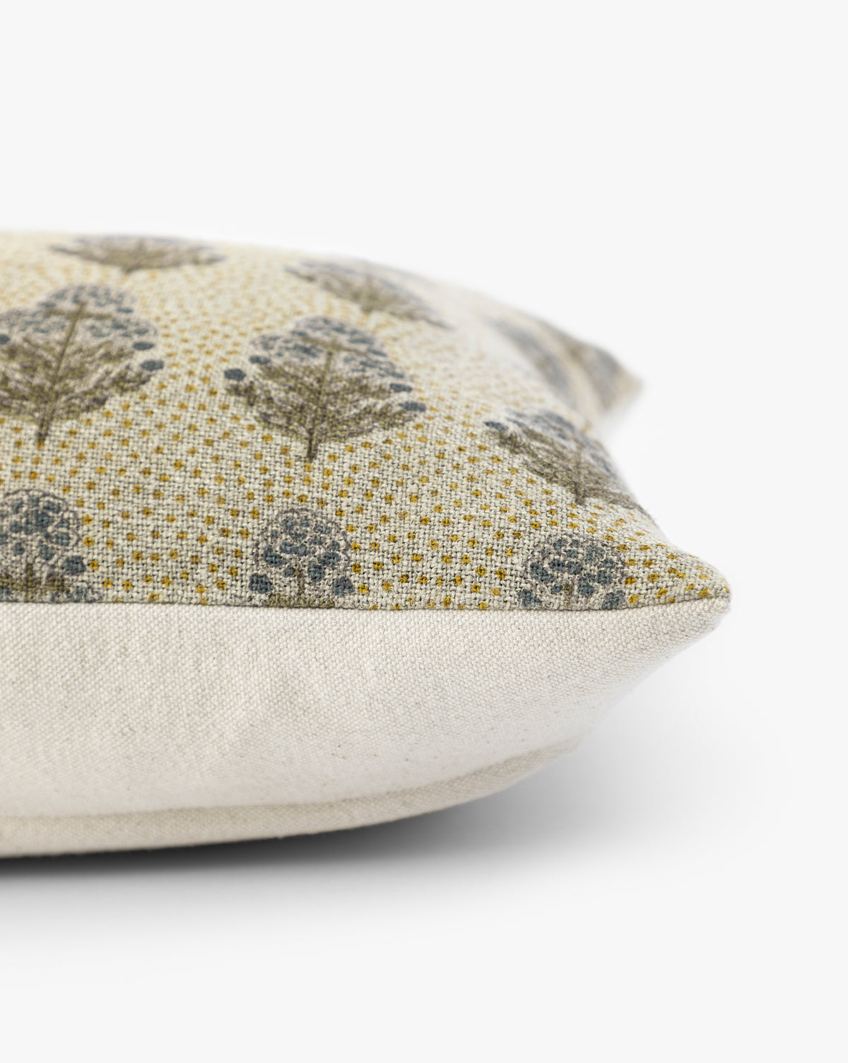 A close-up side view of the Patricia Pillow Cover, featuring textured beige fabric and a gray leafy tree pattern on a yellow background with earthy tones, displayed on a white surface, by Vendixs