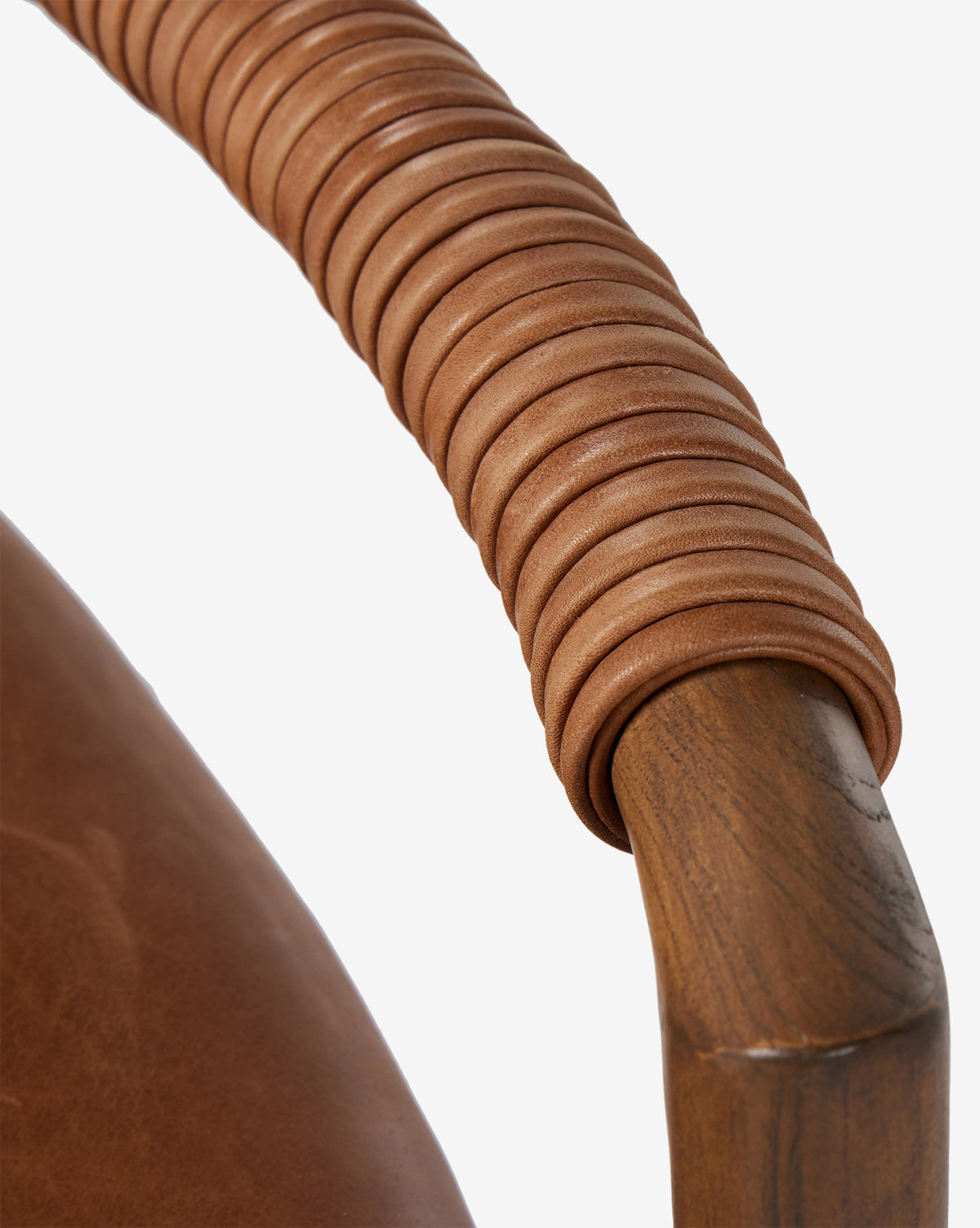 Close-up of a Four Hands Patrin Stool armrest in ash wood, wrapped with light brown leather loops, beside a matching performance-upholstered seat. Vendixs