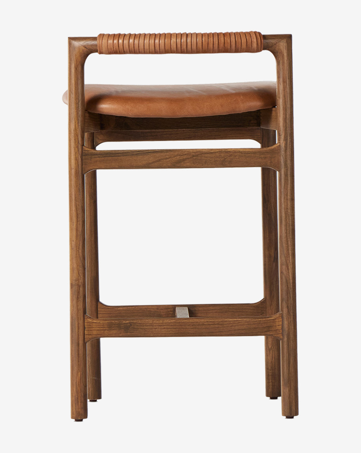 The Four Hands Patrin Stool has an ash wood frame and a tan leather seat with wrapped leather detail on the top rail, shown from the front against a white background. Vendixs