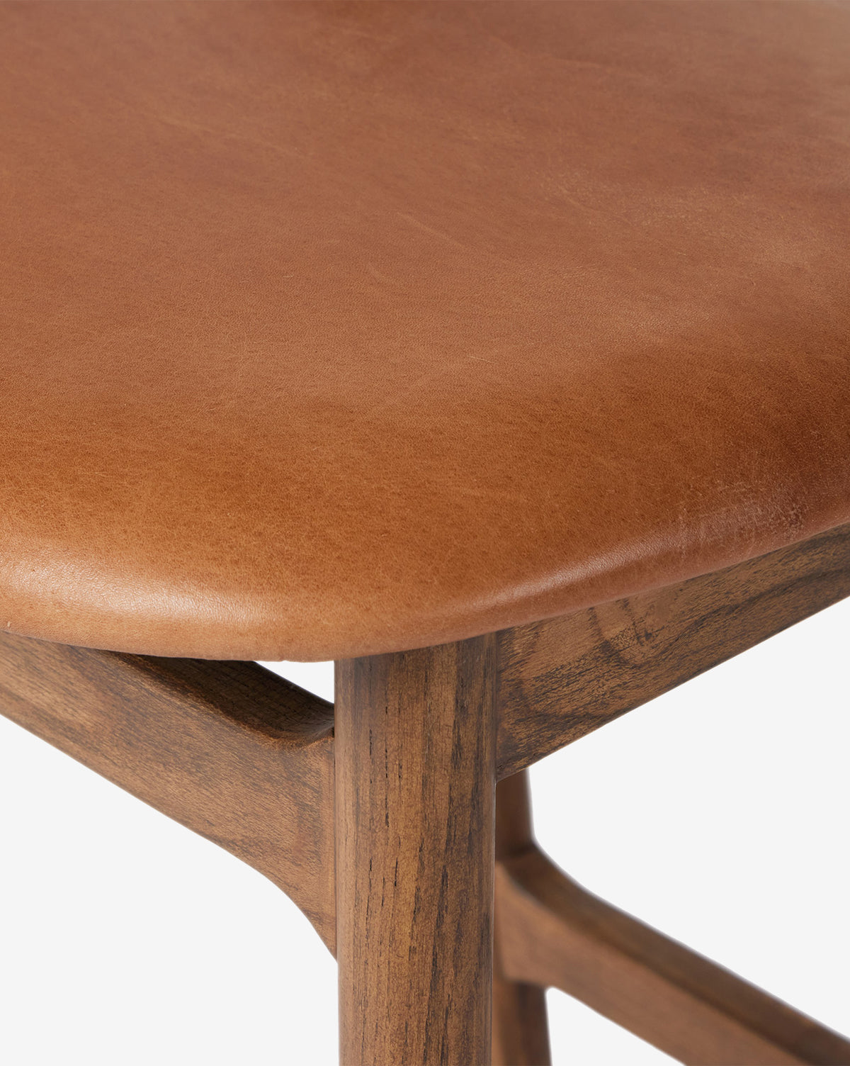 Close-up of the Four Hands Patrin Stool, featuring an ash wood frame and a smooth light brown performance upholstered seat, showcasing quality texture and craftsmanship. Vendixs