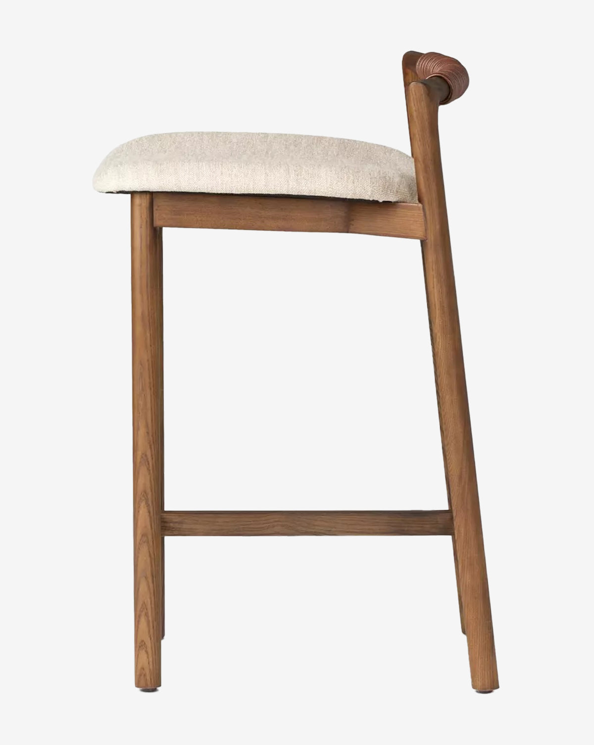 The Patrin Stool by Four Hands has an ash wood frame, angled backrest, beige performance-upholstered seat, and footrest, shown in side profile against a plain white background. Vendixs