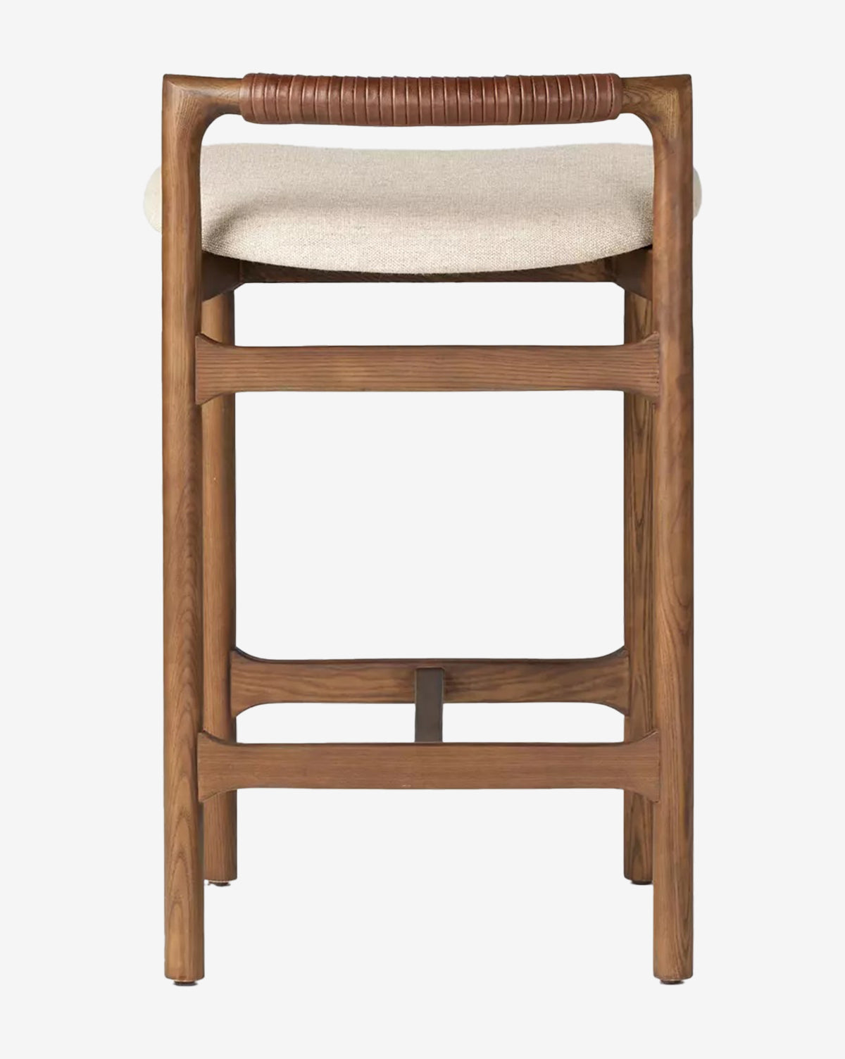 The Patrin Stool by Four Hands features an ash wood frame, light beige performance upholstery, a footrest, and a brown leather-wrapped backrest, shown from behind against a white background. Vendixs