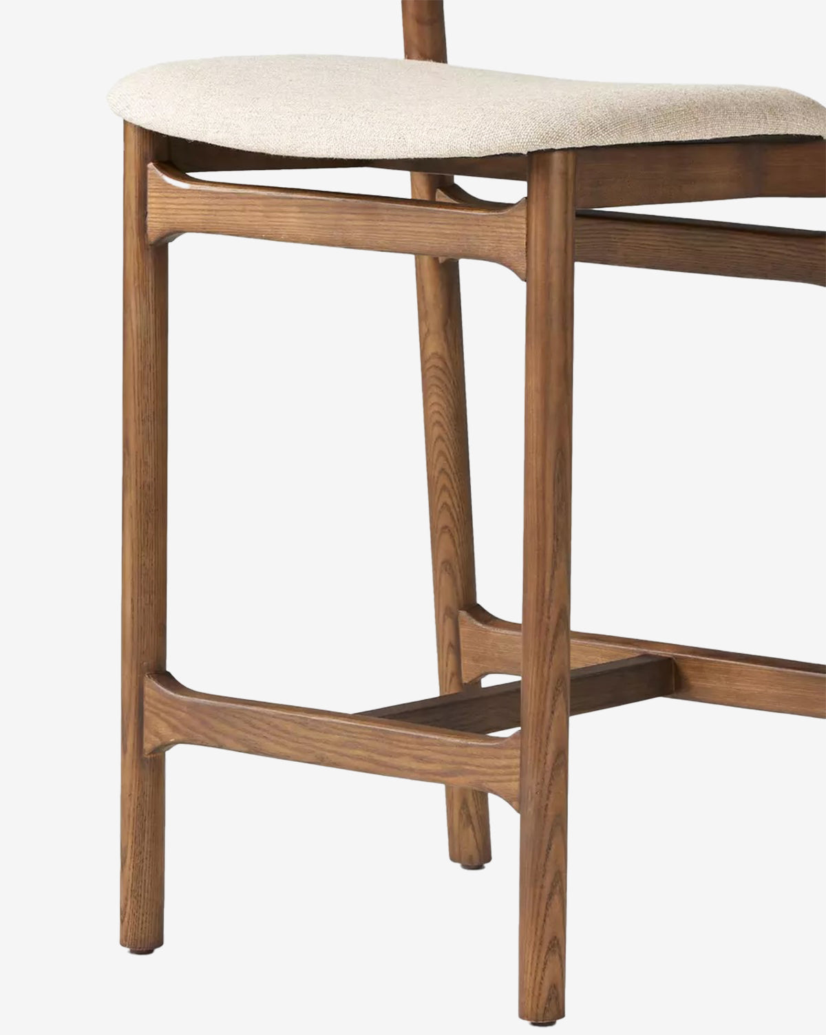 A close-up of the Four Hands Patrin Stool highlights its performance light beige upholstered seat, minimalist design, and medium-toned ash wood legs and frame with visible grain, Vendixs