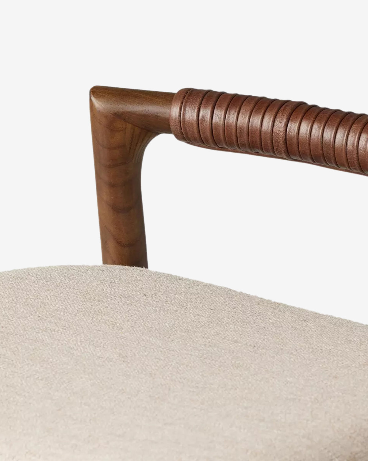 Close-up of a Four Hands Patrin Stool’s dark ash wood armrest wrapped in brown leather, with a light beige performance seat, set against a plain white background. Vendixs