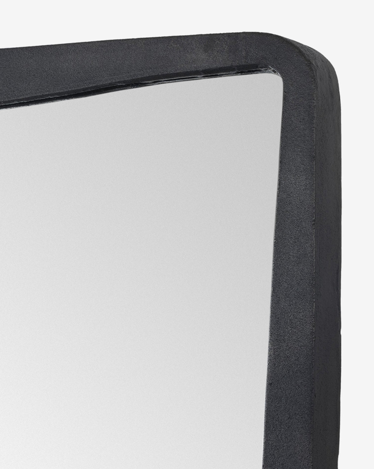 Close-up of the Penrod Floor Mirror’s corner, showcasing its thick, black, subtly textured cast aluminum frame against a plain white background—a striking sculptural accent for any home, by Vendixs