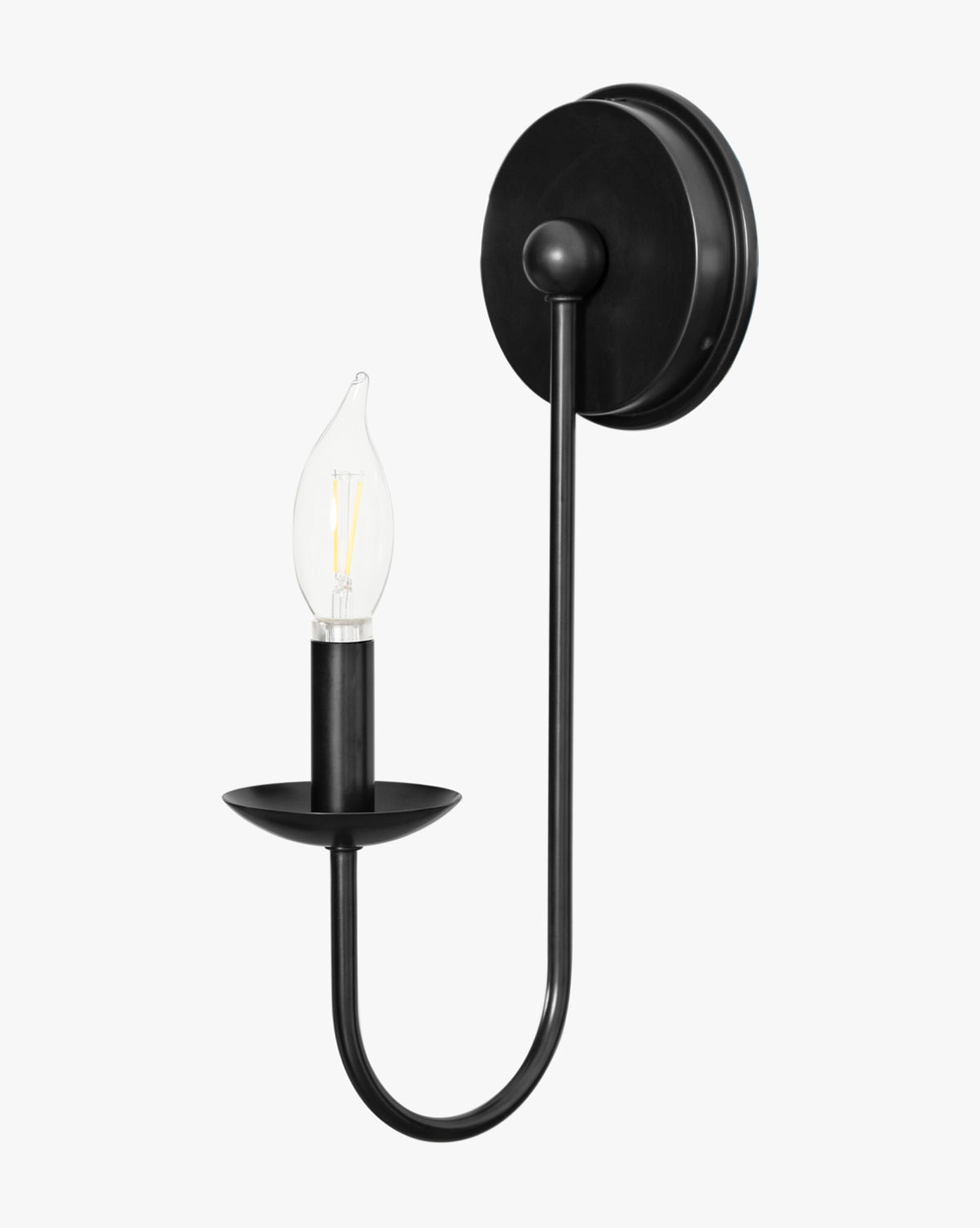 The Philomena Single Sconce by Makerspalm features a black metal frame with a round base and curved arm, holding an exposed candle-shaped bulb on a circular plate for modern wall lighting by Vendixs