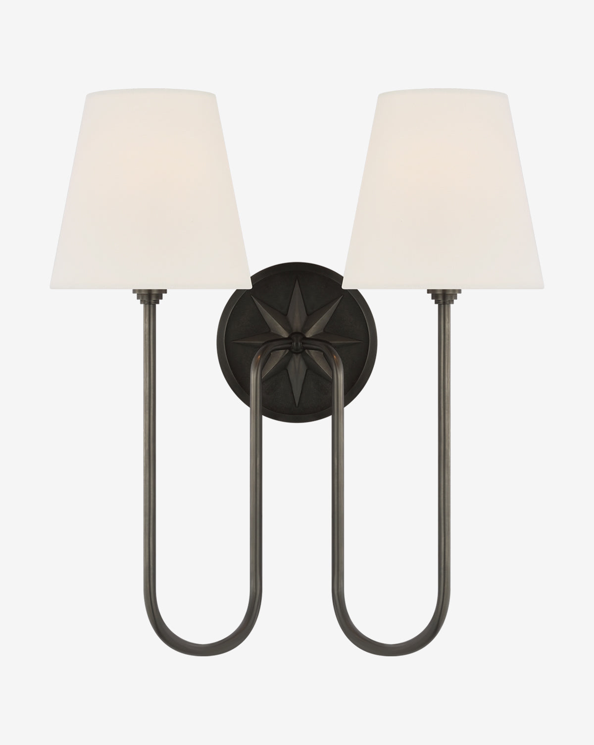 The Polaris Double Sconce by Visual Comfort & Co. Signature adds classic elegance with swooped arms, tapered white linen shades, and a dark circular base featuring a striking starburst design. Wall-mounted for sophisticated style in any space by Vendixs