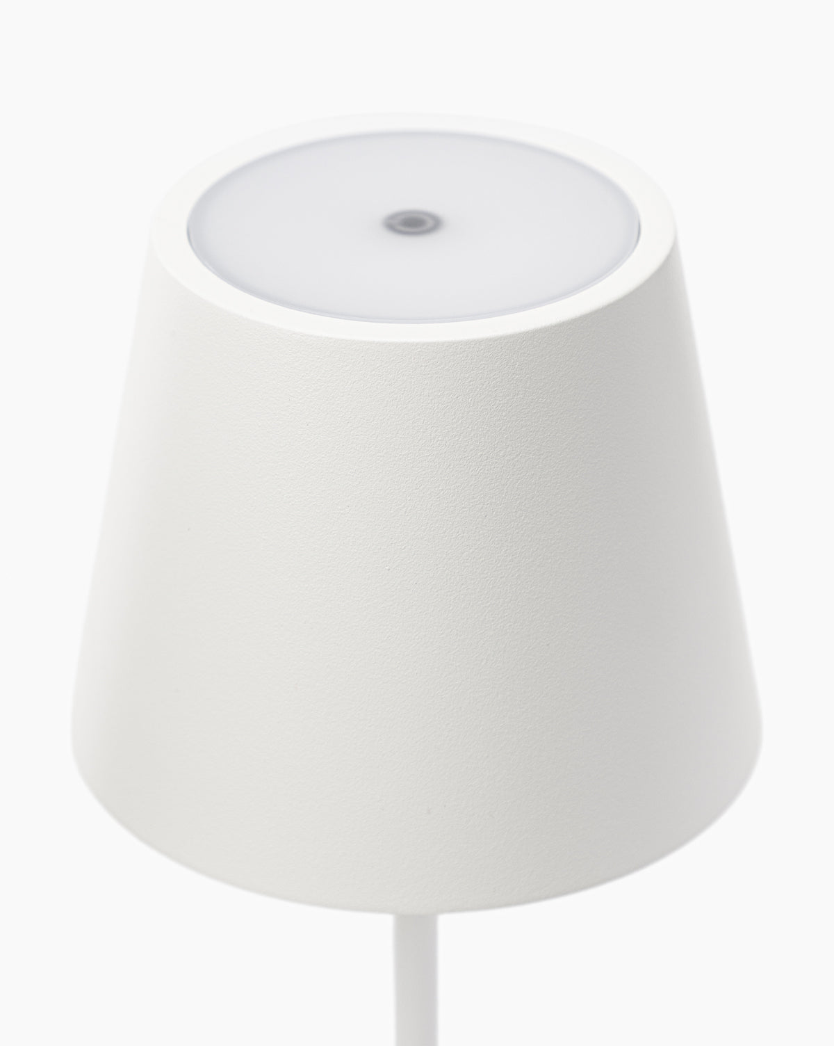 The Poldina Indoor/Outdoor Table Lamp features a minimalistic white conical shade and smooth, circular top, exuding modern elegance. Photographed from above against a plain white background, its sleek design fits any contemporary space by Vendixs